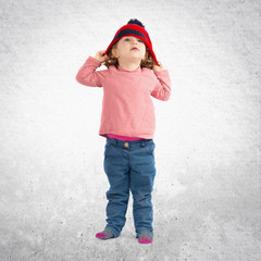 Little girl puttining on a Christmas hat over white background