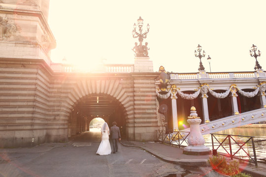 Bride and groom in the sunlight near a bridge