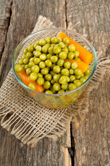 canned peas and carrots on wooden surface