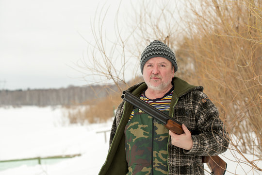 A hunter with a rifle in winter snowy landscape