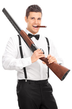 Young man holding a rifle and smoking cigar