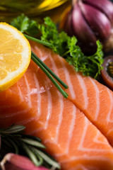 Portion of fresh salmon and herbs on black background