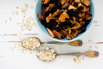 Two tablespoons of oatmeal lying on a white wooden background