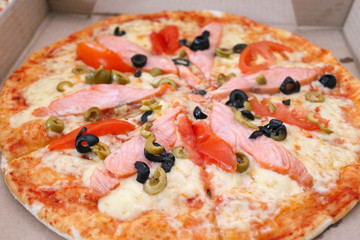Pizza with smoked salmon and olives in paper box