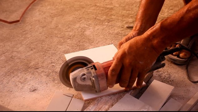 Close up of craftsman is cutting floor tile with portable angle