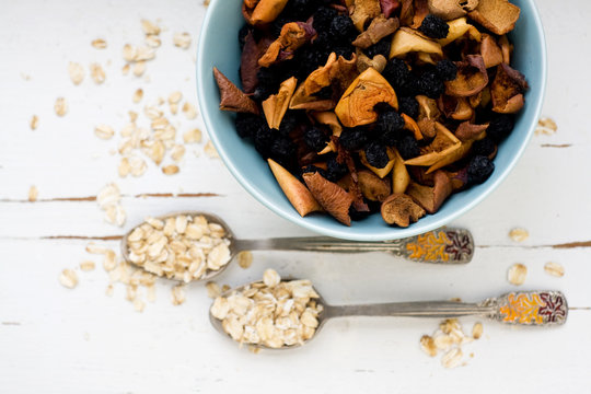 Two tablespoons of oatmeal lying on a white wooden background