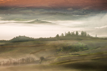 Fantastic Tuscan landscape in the fog and the light of the risin