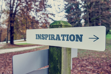 Inspiration signboard on a wooden post with a right pointing arr