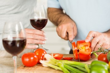 Mature couple having red wine while making dinner