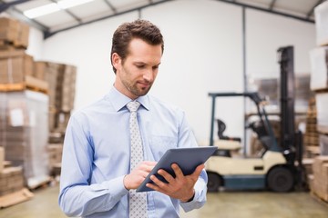 Manager using digital tablet in warehouse