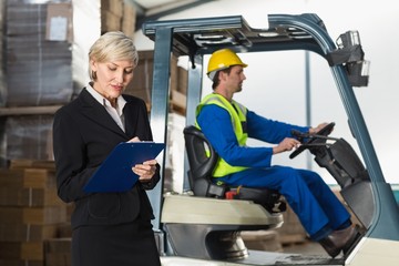 Manager writing on clipboard in front of her colleague