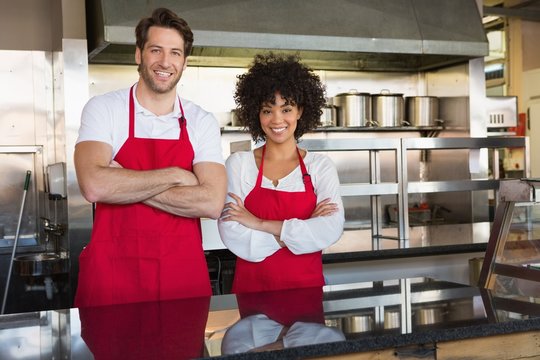 Smiling Colleagues In Red Apron With Arms Crossed