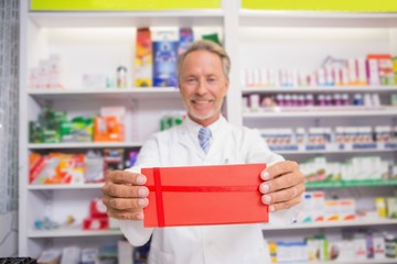 Fototapeta premium Smiling senior pharmacist presenting paper