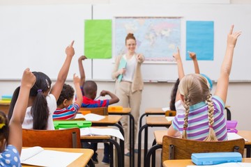 Pupils raising hand during geography lesson in classroom