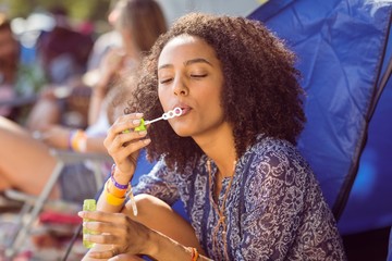Carefree hipster blowing bubbles in tent