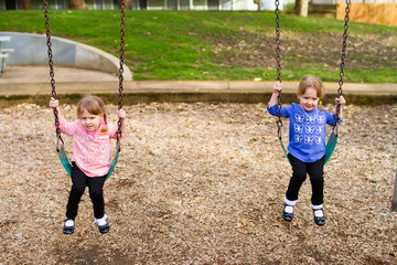 Identical Twins At Park On Swings