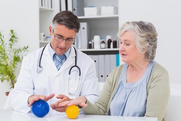 Physiotherapist guiding female patient with massage ball