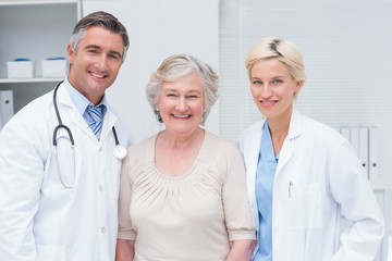 Doctors and senior patient smiling in clinic