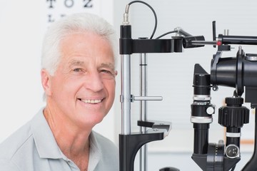Happy senior man in front of slit lamp
