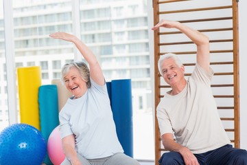 Senior couple doing stretching exercise in gym