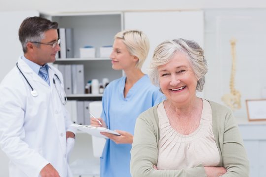 Patient smiling while doctor and nurse discussing in background