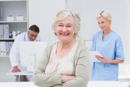 Patient smiling while doctor and nurse working in background