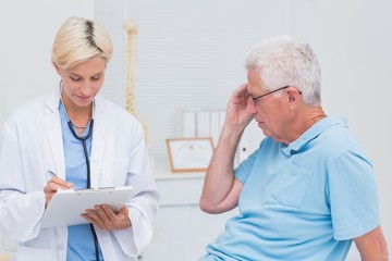 Obraz premium Doctor writing prescription for senior patient