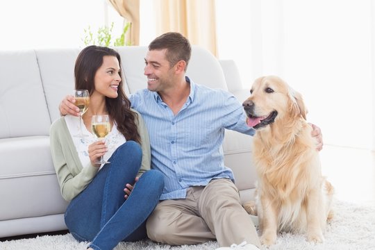 Couple holding wine glasses while sitting with dog
