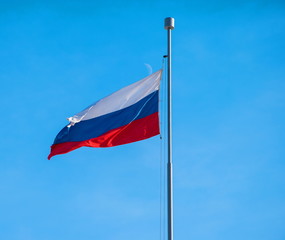 Russian State tricolor flag against the blue sky