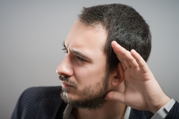 Obraz premium Businessman holds his hand near his ear and listening something