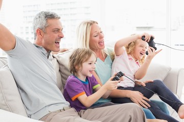 Fototapeta premium Family playing video game while sitting on sofa
