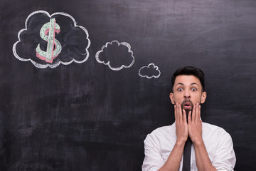 Frightened businessman with dollar sign painted on chalkboard