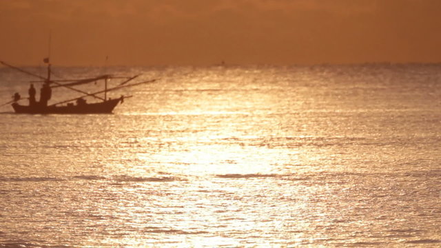 Fishing boat moves through the water at sunset.