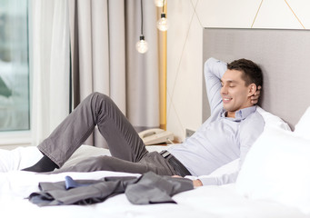 happy businesswoman lying in bed in hotel room