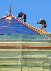 Roofers are working on the roof of an old building