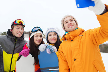 happy friends with snowboards and smartphone