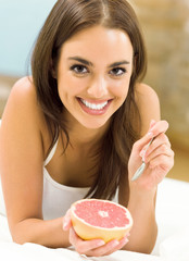 Portarit of young woman eating grapefruit