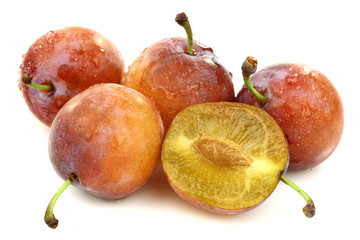 four fresh ripe plums and a cut one on a white background
