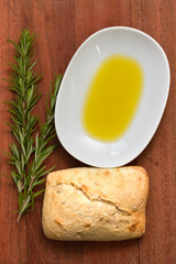 rosemary, bread and oil on brown background