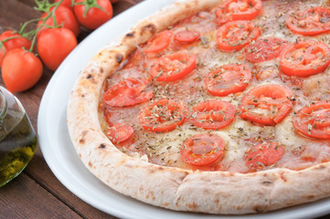 Fresh tomato and mozzarella pizza on wooden table