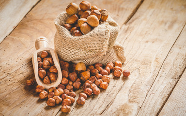Hazelnuts in a rural bag on a wooden table and a spoon for scoop