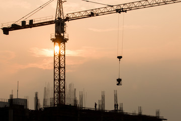 Industrial landscape with silhouettes of cranes on the sunset