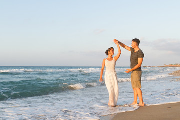 Young couple enjoys walking on a hazy beach at dusk.