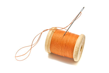 spool of orange thread and needle