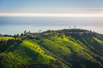 View of green hills and houses overlooking the Pacific Ocean, in © jonbilous
