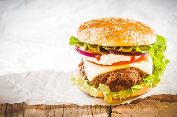 Tasty hamburger with fast food in a white paper on the wooden ta