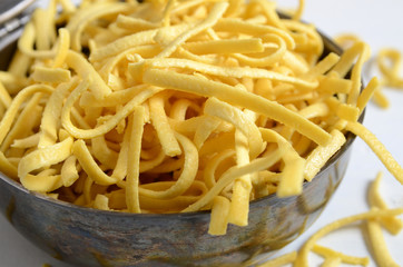 Raw, uncooked pasta in a metal pot with a lid