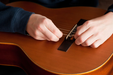 hands are stringing a guitar