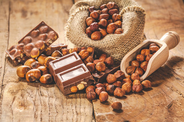 Milk chocolate with nuts on a wooden spoon in a country style.