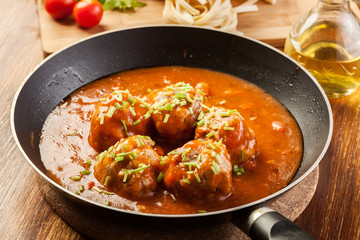 Meatballs with tomato sauce on black pan